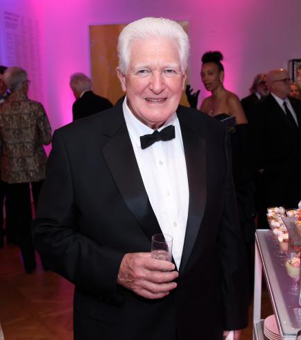 Photograph of a man in black tie smiling at the camera